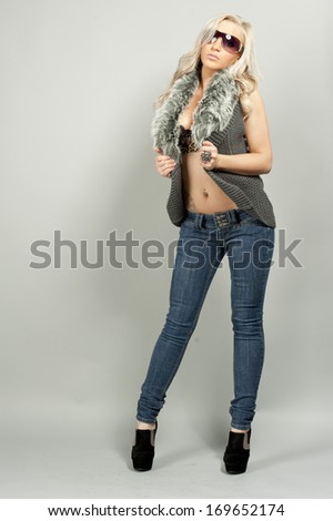 A young female model wearing jeans in a studio setting.