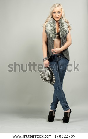 A young female model wearing jeans in a studio setting.