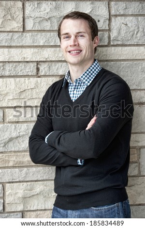 Happy young white male model posing on a stone background.