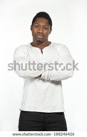 An African American male model wearing a white casual t-shirt with black pants in a studio setting on a white background while looking at the camera.