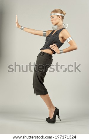 A young female model posing on a gray background wearing futuristic elements on her.