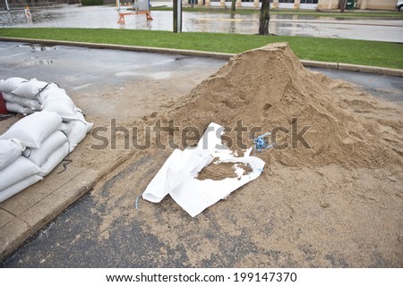 A pile of sand on the ground being used to make sandbags.