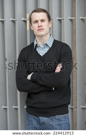 An attractive young male model posing on a gray steel background.