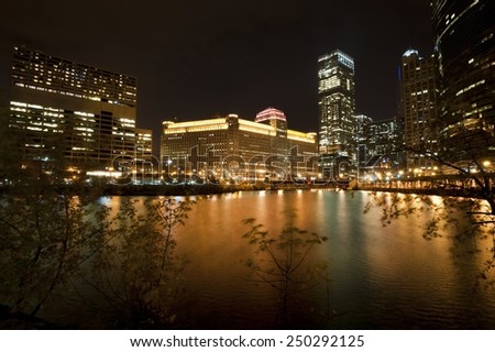 A view of the Chicago river and the Merchandise Mart with other commercial buildings at night.