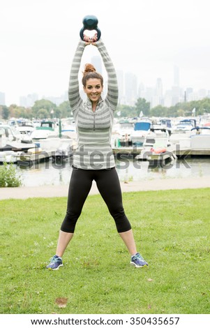 A beautiful sexy girl doing workout inside a park. Few boats and high rise buildings is be seen at the background.