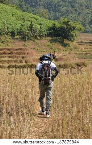 Young man with backpack to hiking summer mountain