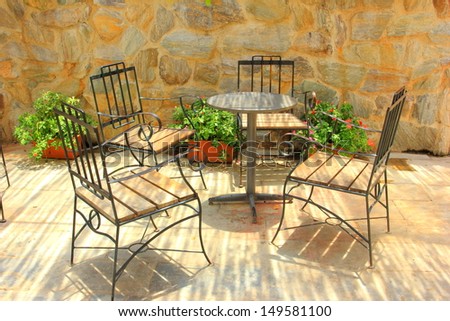 Table and chairs front of stone wall.
