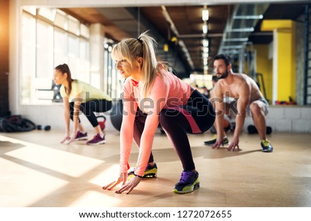 Young tired athletes in a gym stretching their leg muscles after pilates class.
