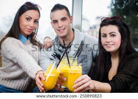Young people sitting in cafe and drinking juice.