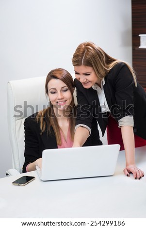 Female discusses work on computer with assistant in an office setting.