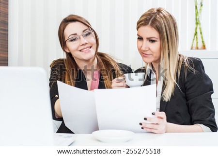 Business meeting, showing contract document, casual conversation with coffee at office, two beautiful females.