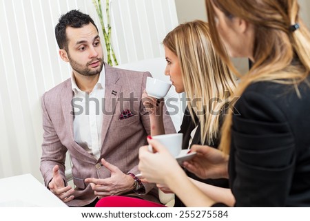 Business meeting, casual conversation with coffee at office, one man two beautiful females.