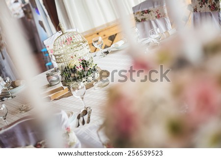 Wedding table decoration in restaurant. Bird cage, vintage. Shallow depth of field.