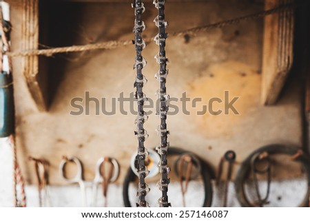 Chain chainsaw hanging in the workshop. Dirty, rusty, shallow depth of field.