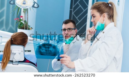 Consultation at dentist office. Female doctor consults handsome doctor in background. Shallow depth of field.