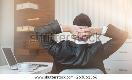 Successful businessman sitting in chair at office.