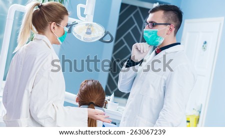 Dentist and his female assistant have conversation before surgery. Dentist operation room.