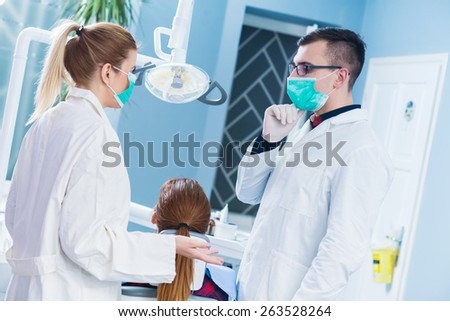 Two doctors consults before surgery at dentist office.