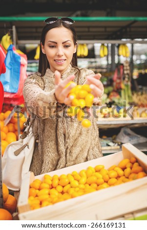 Beautiful female choosing fresh fruits ready for sale at marketplace. Shallow depth of field.