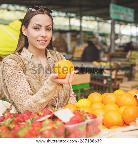 Beautiful female looking for fresh fruits ready for sale at marketplace.