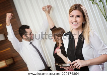 Portrait of successful business woman at happy work place. Happy people in background.