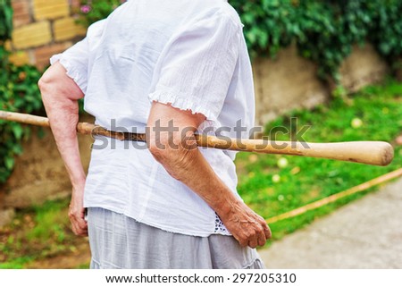 Old grandmother walking with crutch on she\'s back. Retirement.