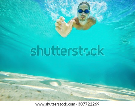 Underwater shot. Swimmer extends his hand to take the camera from the bottom of the sea. Deep blue sea. Wide angle shot.