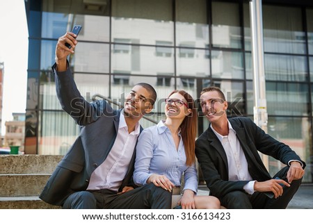 Group of business people taking selfie and looking at mobile phone. Shallow depth of field.