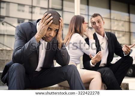 Gossip colleagues in front of their office sitting at stairs, handsome businessman portrait in front and gossip out of focus in background.