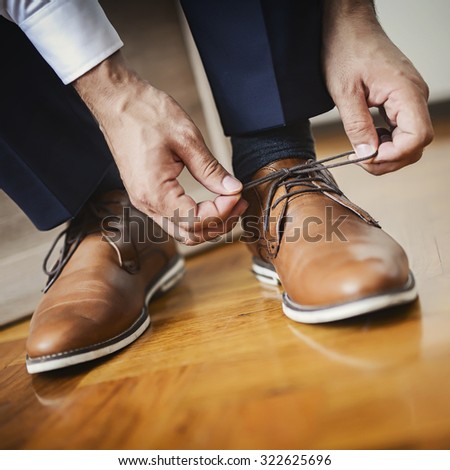 Businessman or groom tied a shoelace on his brown shoes. Shallow depth of field.
