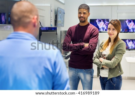 Young couple at tech store looking at seller.