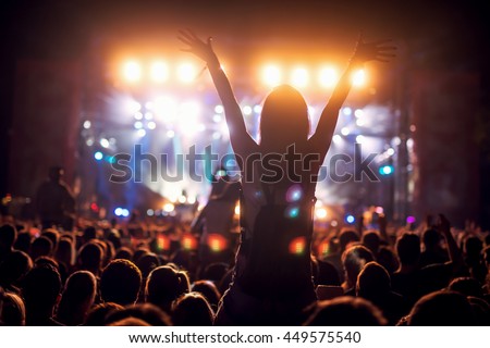 Girl on shoulders in the crowd at a music festival.