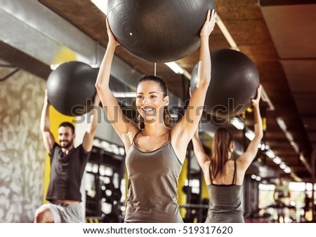 Healthy young people working out with pilates ball at a gym.