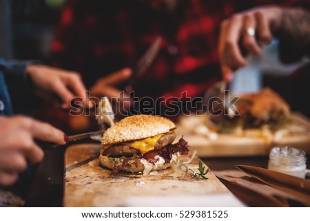 Friends enjoying together in delicious taste of burgers.