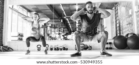 Black and white photo of a man and woman working out at gym.