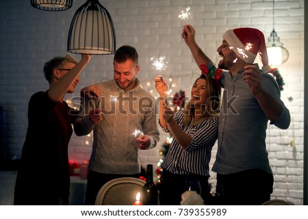 Group of smiling friend having fun with sparkles at home for Christmas in the night.