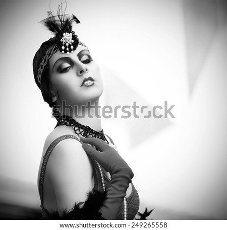 Black-and-white retro style depiction of a woman in typical style of the 1920s or 1930s. She\'s fashionably adorned in black lace, pearls, evening gloves and a pearl-accented wrap-around headpiece.
