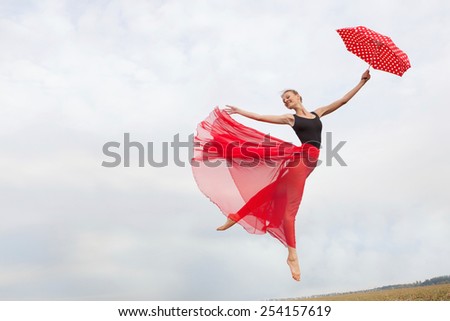 Young Elegant Woman Flying in the Cloudy Sky in the Black Gymnastics Leotard , Red Long Skirt with Red Polka Dot Umbrella