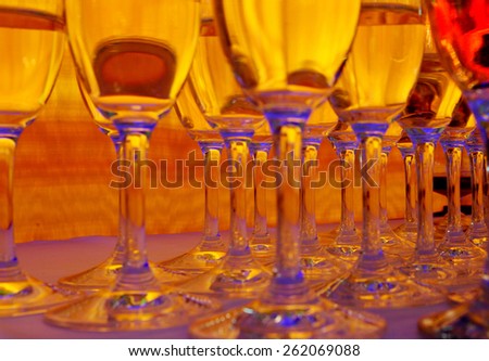 A lot of wineglasses with champagne standing at the colorful background. Yellow, red and blue colors