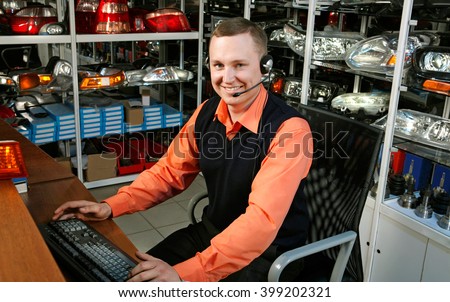 Smiling Salesman Auto Parts Store with a Computer