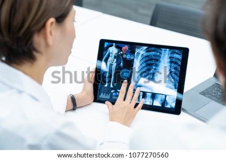 Medical doctors looking at a screen of tablet PC. Medical technology concept.