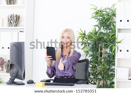 the beautiful girl at office at the computer with reader a thumb up