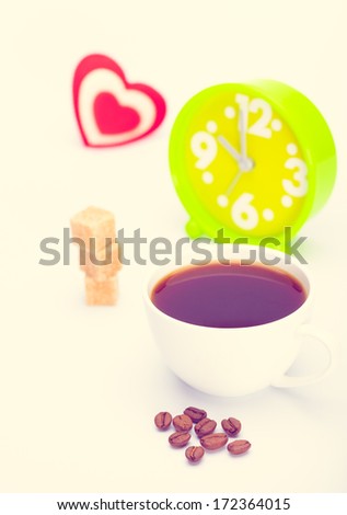 beautiful white cup, coffee, hearts with an alarm clock on a white background. Toned in warm colors