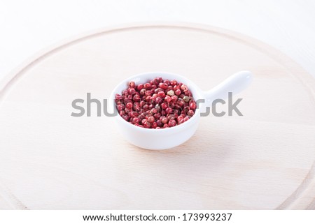 Red bell pepper in a small white plate and wooden round board