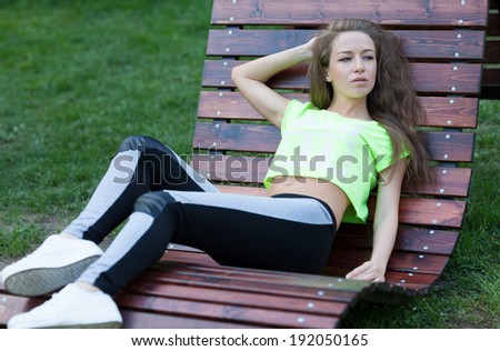 The beautiful girl fitness lies in a wooden chair. Short top sports pants