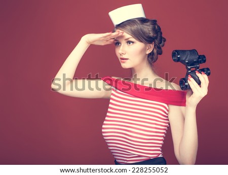 beautiful girl sailor with a vintage binoculars and looks into the distance