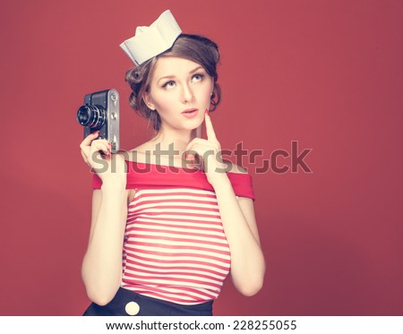 Beautiful pin-up girl holding in his hand a vintage camera