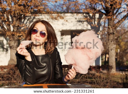 Beautiful brunette girl in sunglasses eating candy floss at a table in summer cafe
