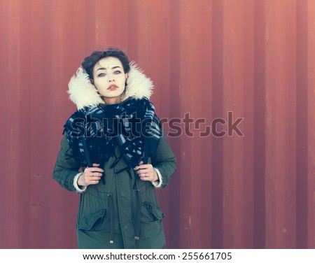 Beautiful unusual girl in green jacket on a red background. Close up, warm color