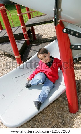 young male child playing on the slide at a playground